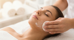 Woman with smooth, glowing skin after dermaplaning, standing in sunlight wearing SPF protection.